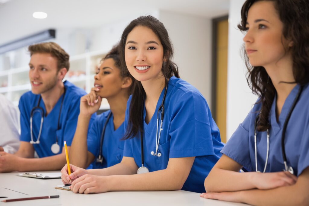 A photo of medical students. The focus is a woman smiling at the camera with long black hair in an over-the-shoulder ponytail. They're all in blue shirts.  Student memberships would be perfect for them.